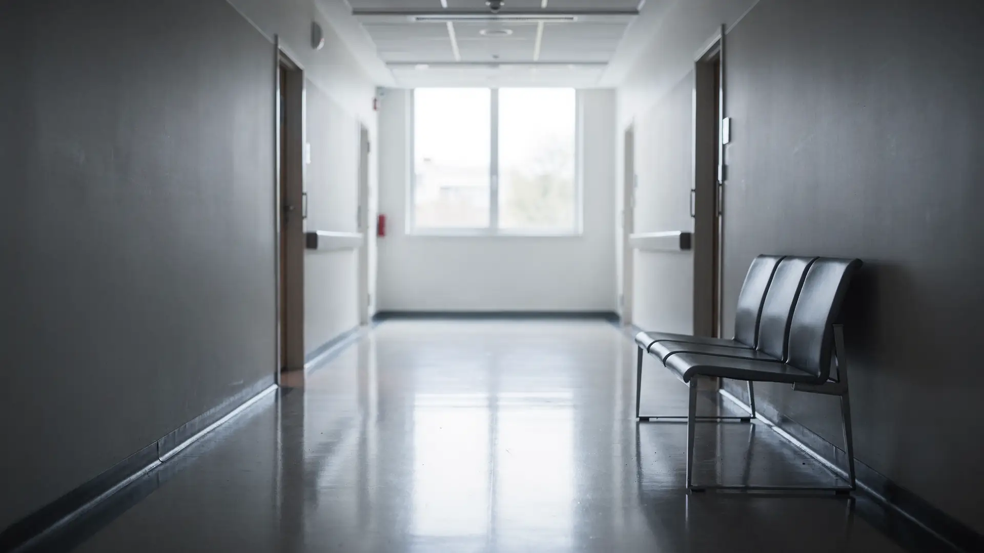 Corredor de hospital vazio com banco de espera e luz natural ao fundo, cena sobre avisar o anestesista antes de uma cirurgia